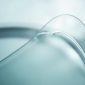 Abstract close-up of a flawless, clear car windshield surface, showcasing subtle iridescent highlights and a smooth texture, indicative of advanced auto glass development for fog resistant and frost resistant properties.