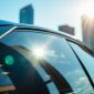 A close-up of a car's tinted window reflecting the vibrant Houston skyline on a sunny day, showcasing the texture of the tint and soft sunlight filtering through, highlighting auto glass protection benefits.